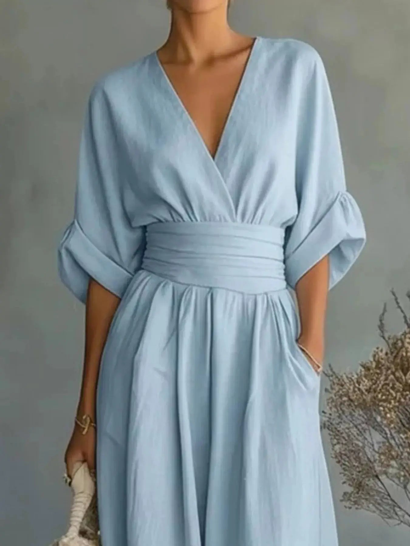 Plus-size light-blue jumpsuit with deep V-neck, ruched waist, and wide-leg pants.