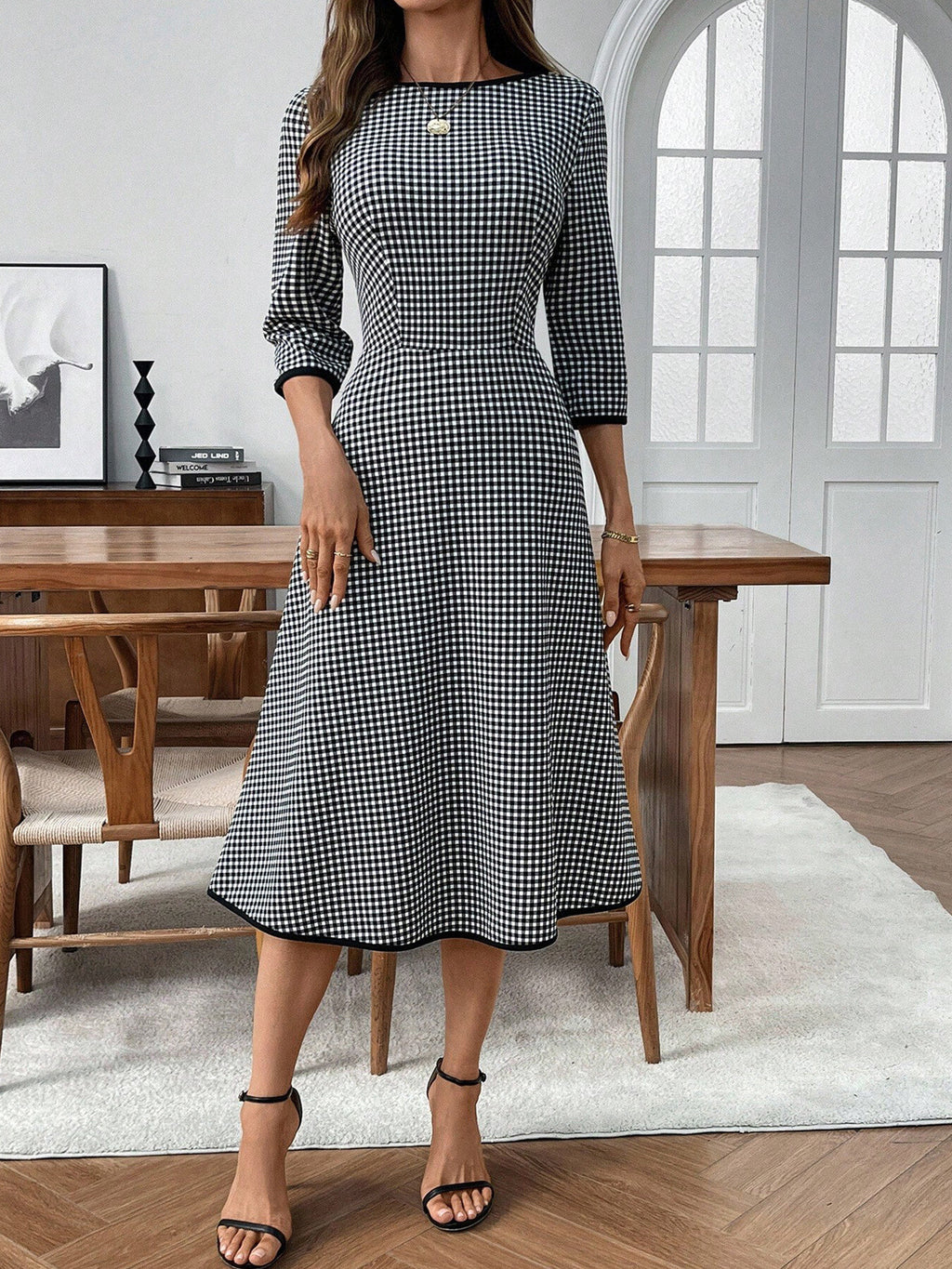 Plaid round-neck 3/4 sleeve dress in black and white; fitted waist with a flared below-knee skirt.