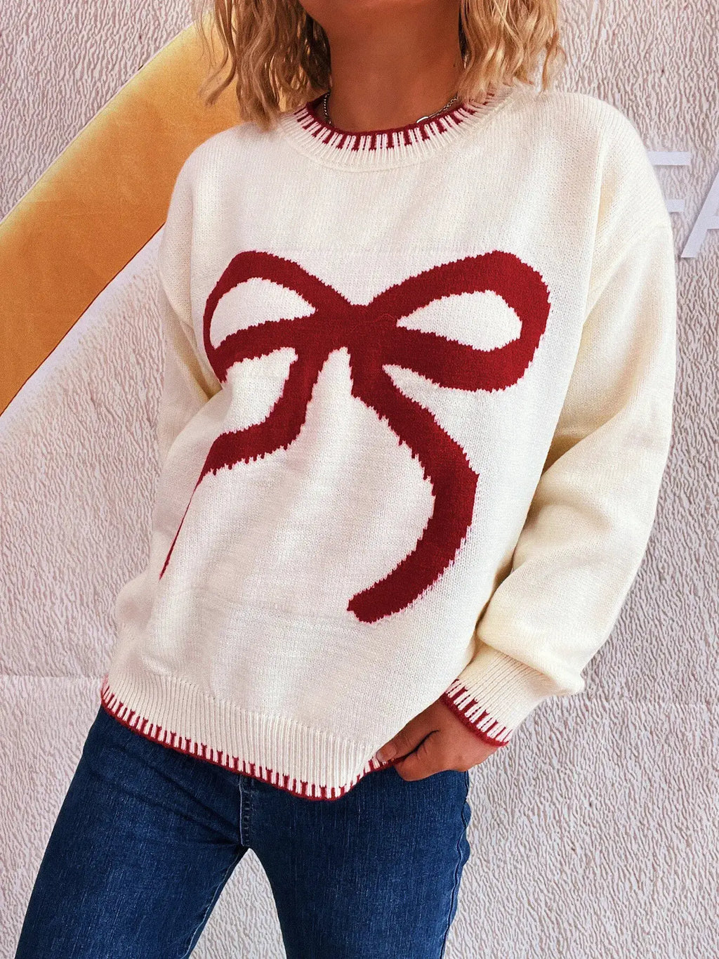 Bow Pattern Round Neck Sweater in white knit with a large red bow graphic; red rib trim at cuffs and hem