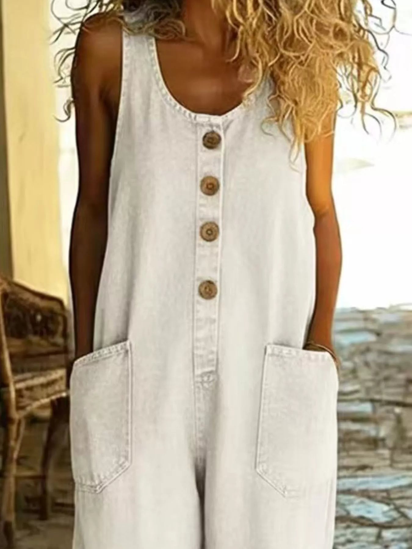Plus-size jumpsuit with button-front, wide straps, and large front pockets in light denim.