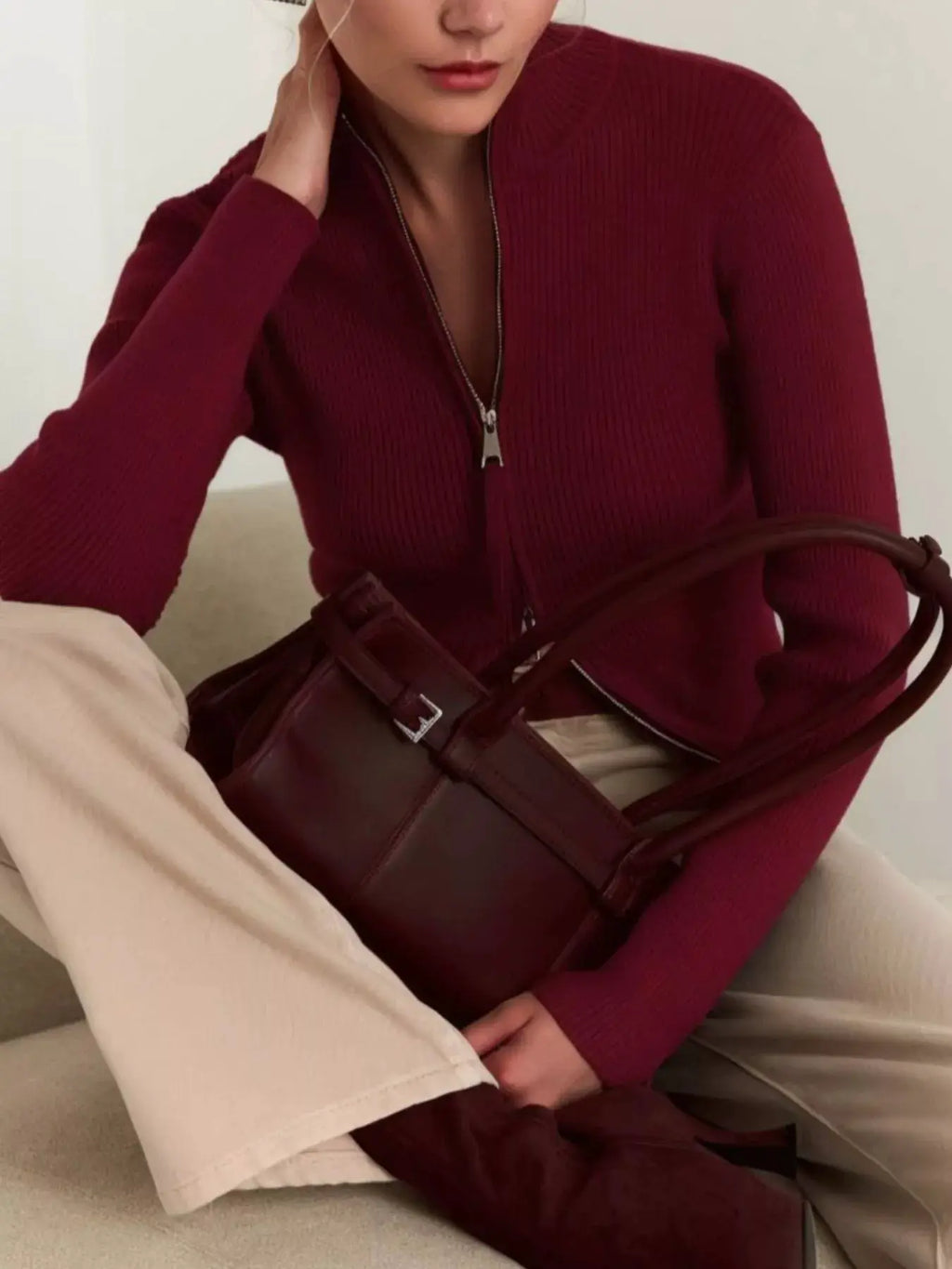 Ribbed knit zip-up cardigan in burgundy, worn by model with beige pants and burgundy bag