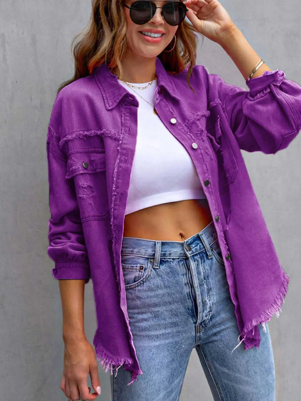 Distressed drop-shoulder purple denim jacket with frayed hems worn over a white crop top