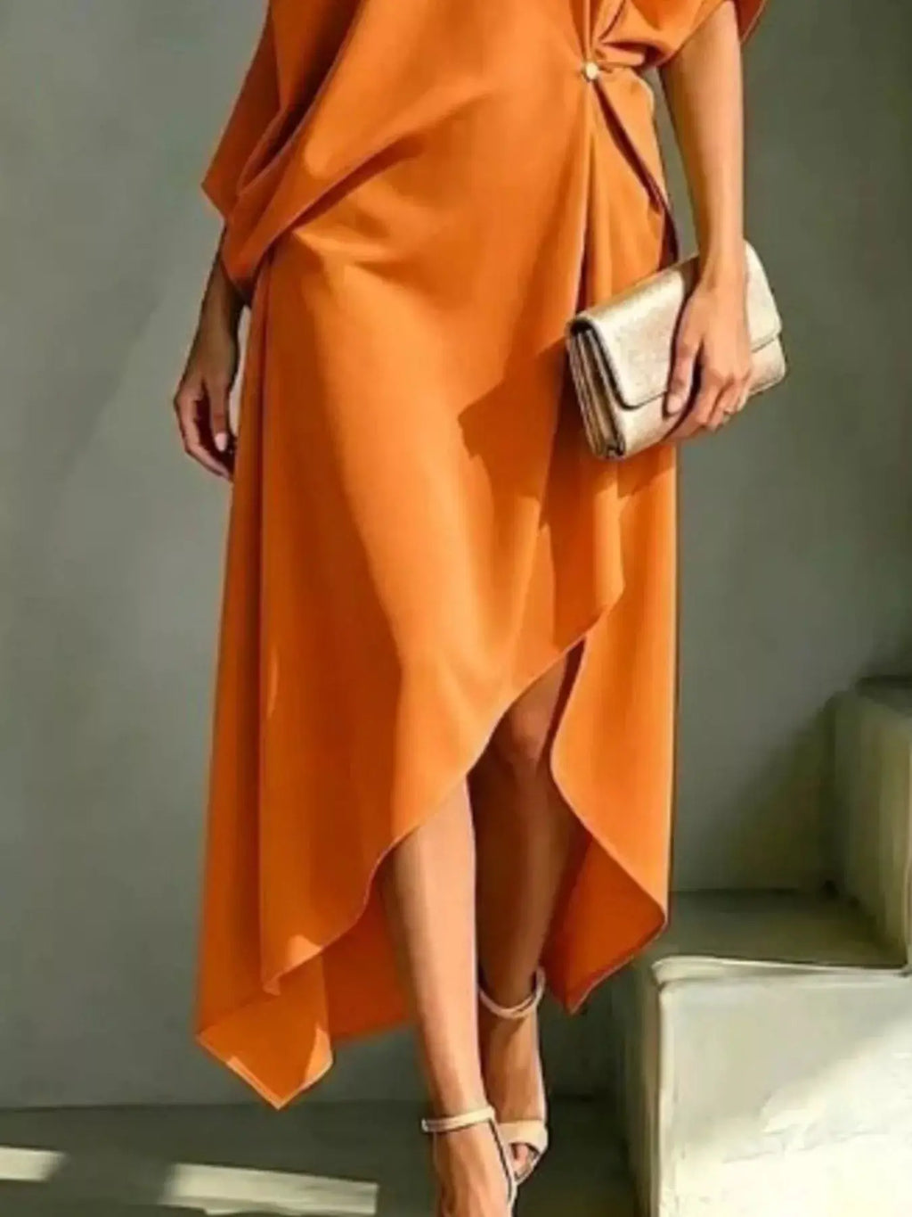 Plus-size asymmetrical one-shoulder drape dress in orange with a beige clutch