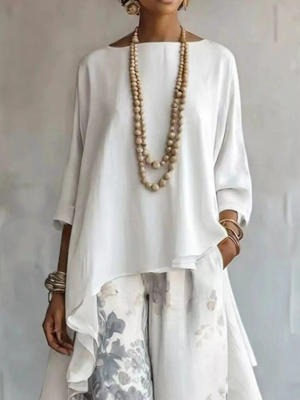 Outfit set with asymmetrical-hem white top and floral-print pants, accented by a long beaded necklace.