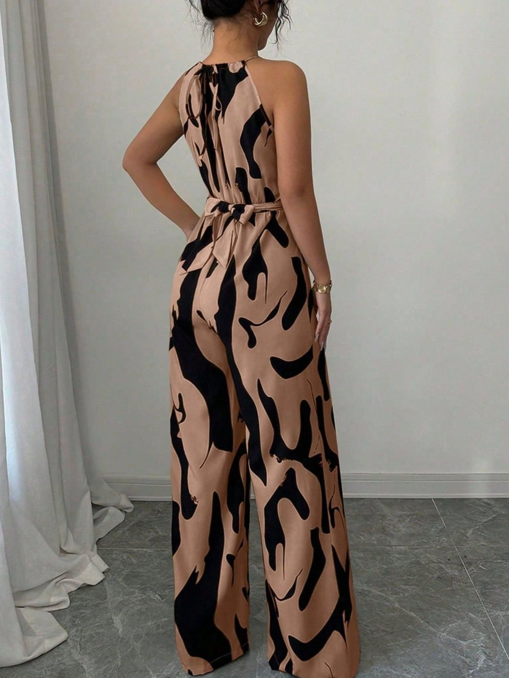 Abstract print sleeveless wide-leg jumpsuit in tan and black with a waist belt