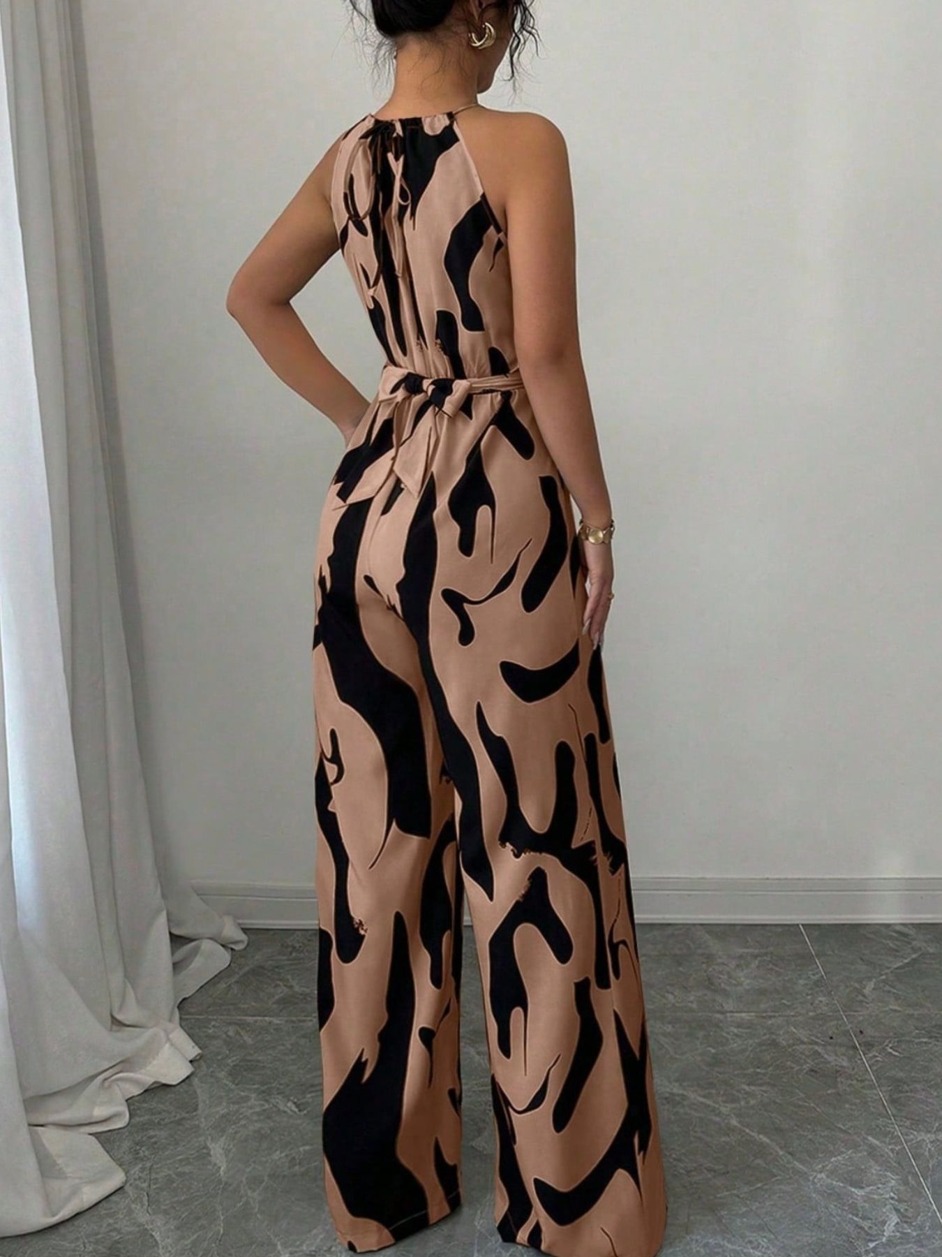 Abstract print sleeveless wide-leg jumpsuit in tan and black with a waist belt