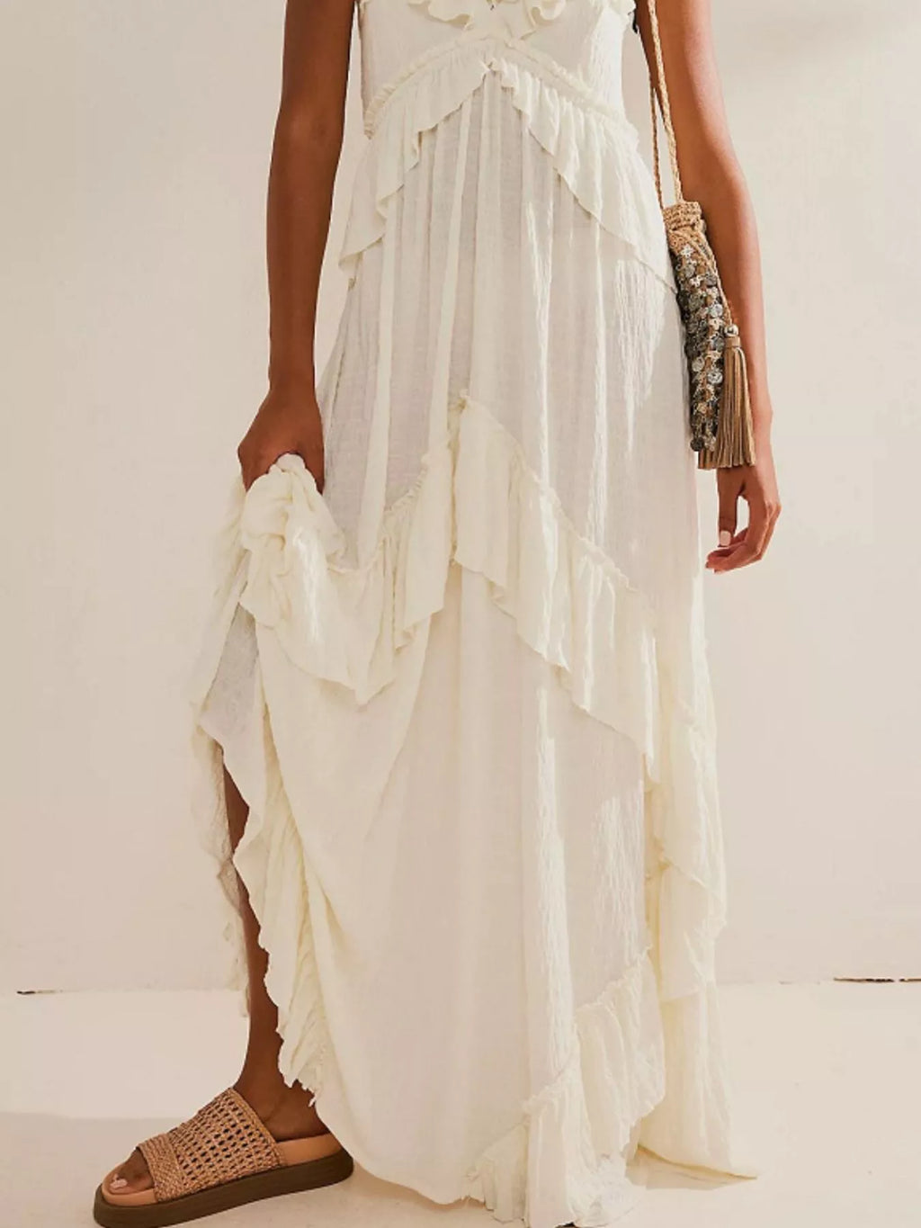 Ruffled halter-neck ivory maxi dress with tied waist and tiered ruffles.