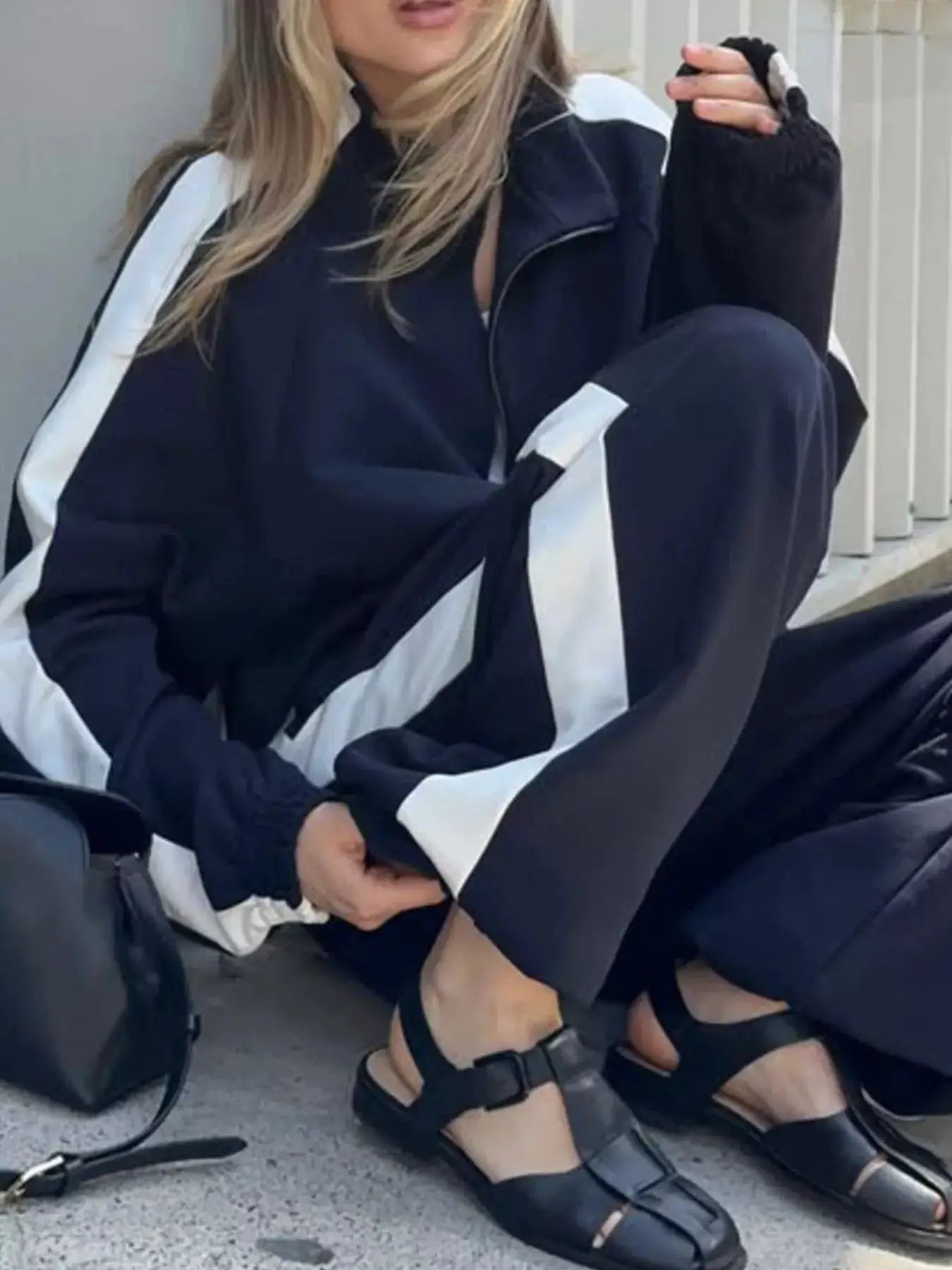 Two-piece zip-up long-sleeve activewear set in navy with white stripe panels on sleeves and pant legs