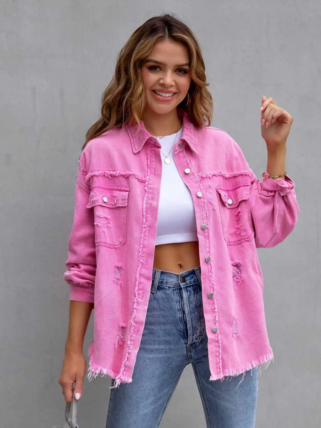 Distressed pink denim jacket with drop-shoulder silhouette worn over a white crop top