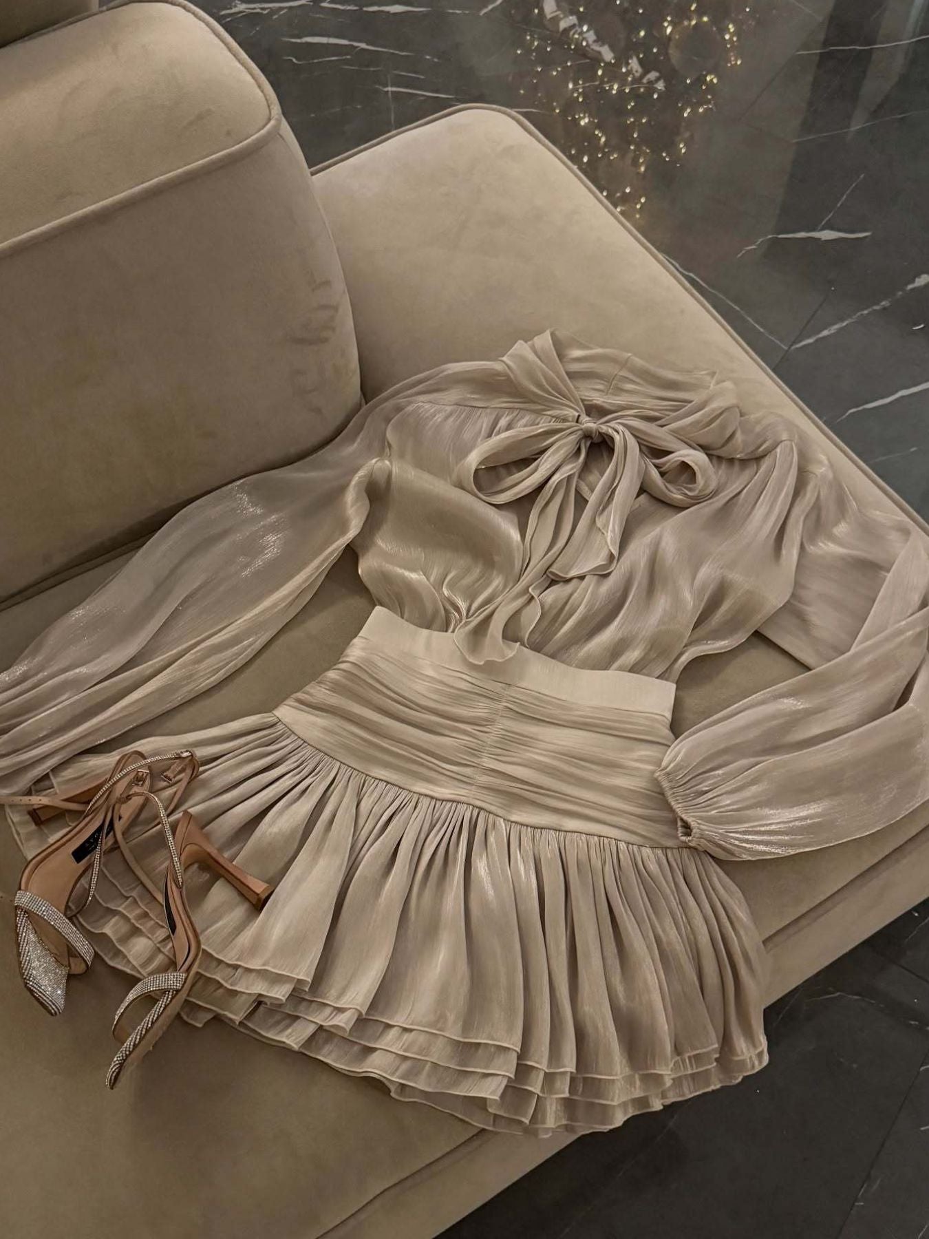 Trendsi Bow-Tie Blouse and Ruched Mini Skirt Set in champagne satin; bow-tie top with ruched pleated skirt.