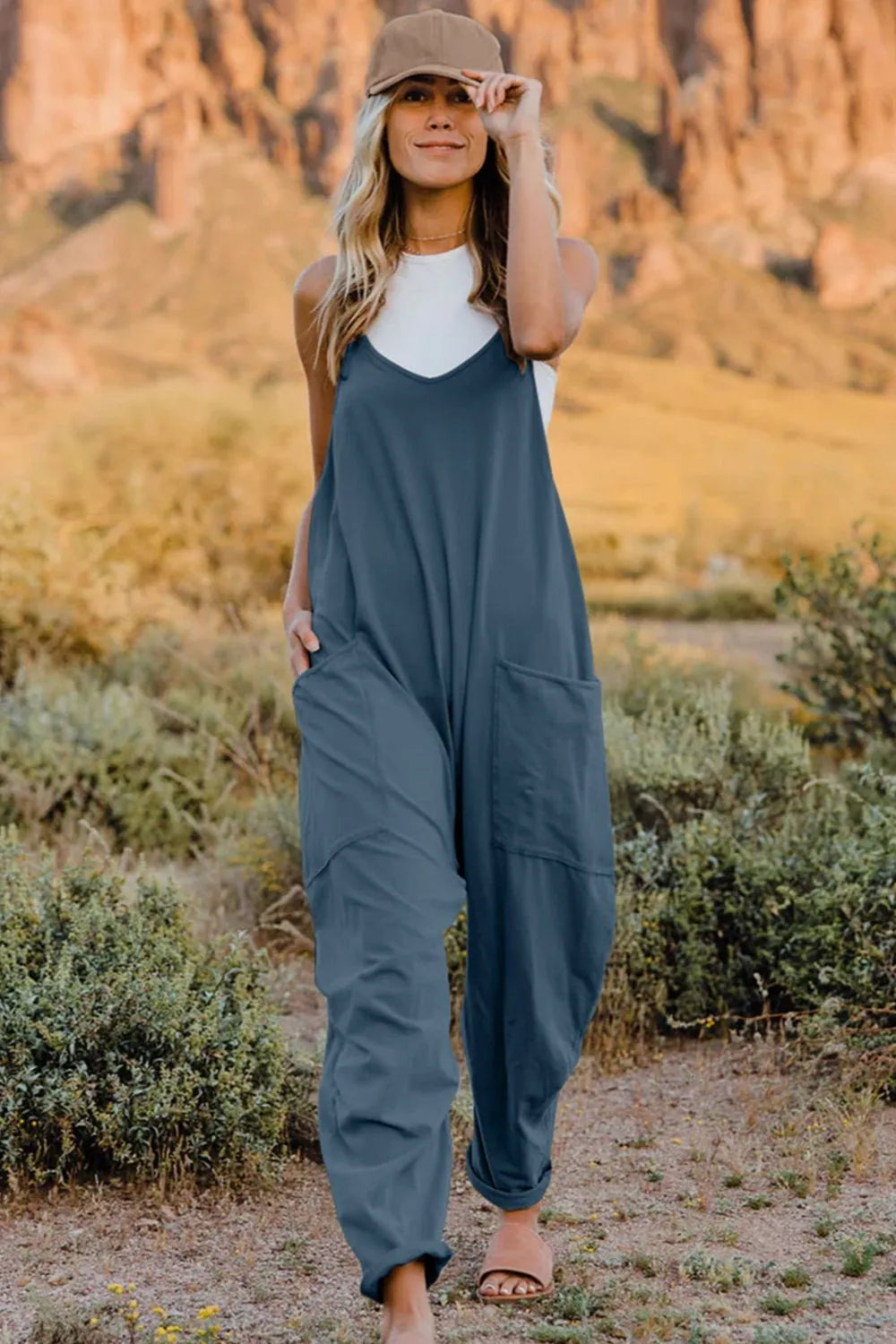 Double Take full-size V-neck sleeveless jumpsuit with pockets in blue, worn by model outdoors.