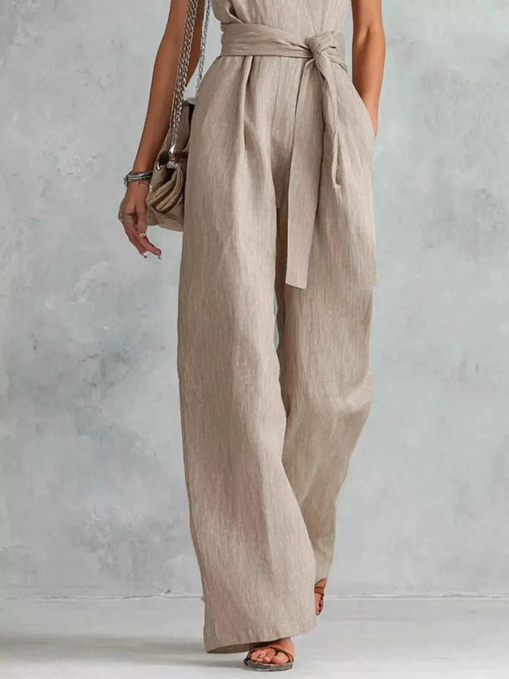 Sleeveless wide-leg jumpsuit in beige linen-like fabric with a waist-tie belt