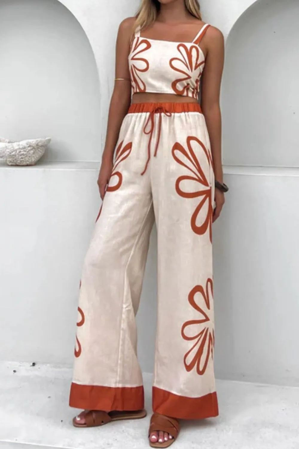 Smocked square-neck cami and pants set by Trendsi in cream with orange floral print; wide-leg pants with orange hem.