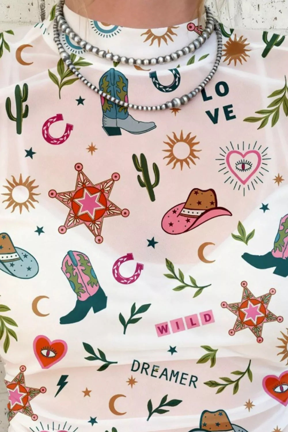 Love Wild Dreamer western-print sheer mesh top in pink with cowboy boots, cacti, and star motifs