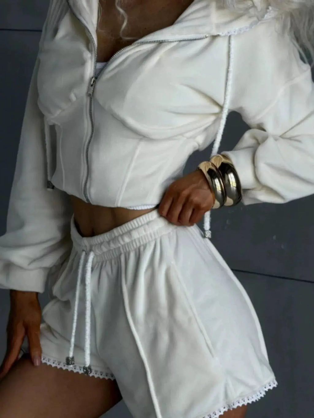 White zip-up hooded outerwear and shorts two-piece activewear set; cropped jacket with drawstrings and lace-trim shorts