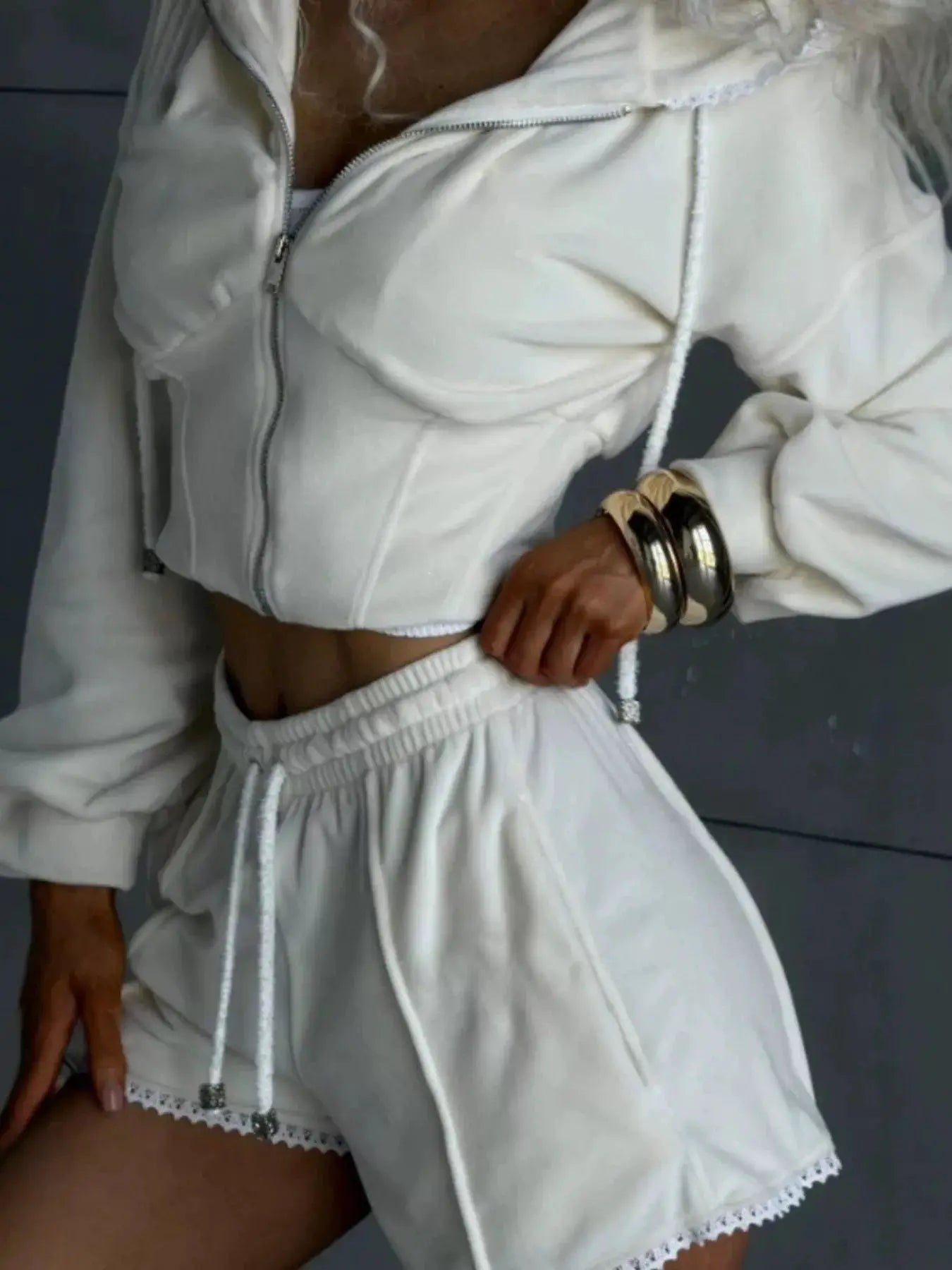 White zip-up hooded outerwear and shorts two-piece activewear set; cropped jacket with drawstrings and lace-trim shorts