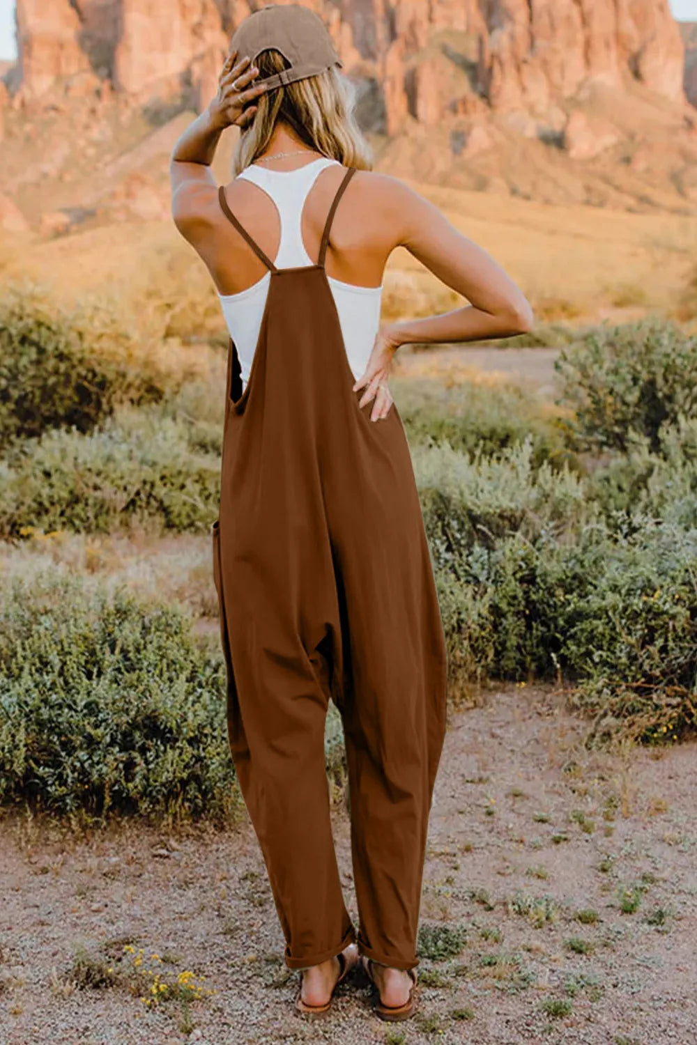 Double Take Full Size V-Neck Sleeveless Jumpsuit with Pockets in brown, worn over a white tank; desert outdoor setting