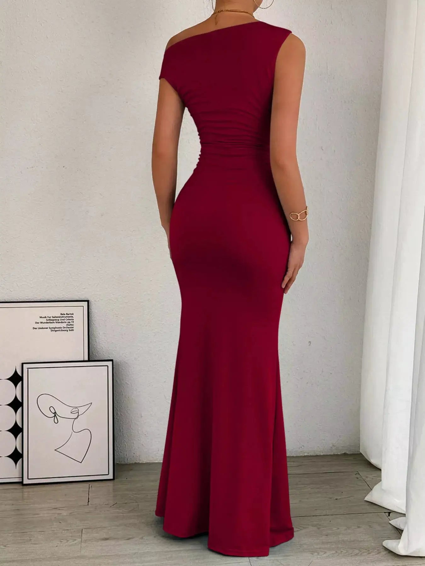 One-shoulder burgundy ruched bodycon maxi dress, back view with a sleek fitted silhouette and floor-length hem