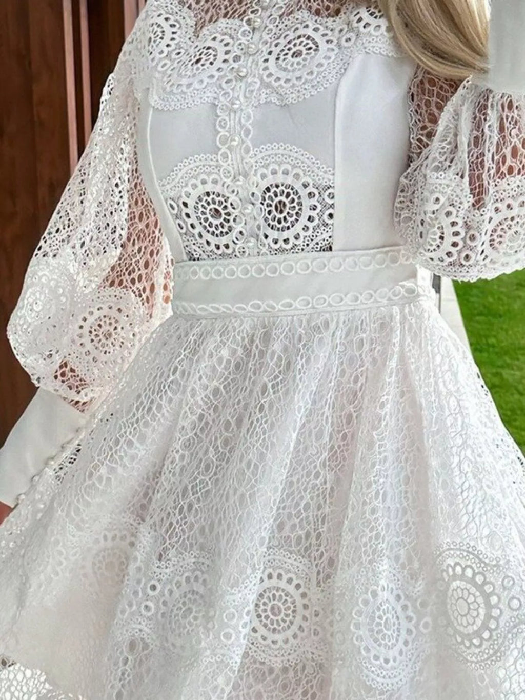 Lace lantern-sleeve mini dress in white with a buttoned back and belted waist with circular lace pattern.