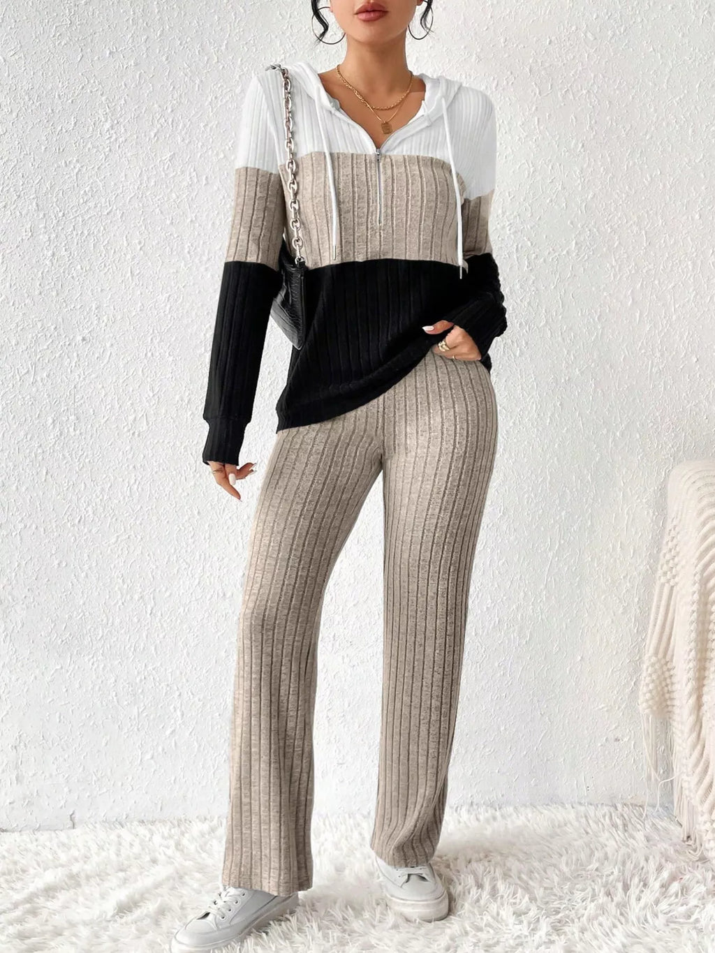 Two-piece color-block ribbed knit activewear set: white, beige, and black hooded top with zipper and drawstring, paired with beige ribbed pants.