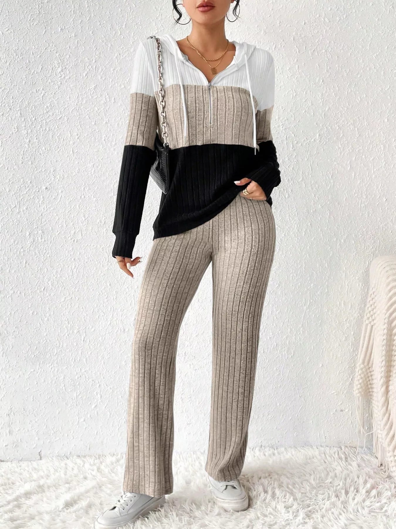 Two-piece color-block ribbed knit activewear set: white, beige, and black hooded top with zipper and drawstring, paired with beige ribbed pants.