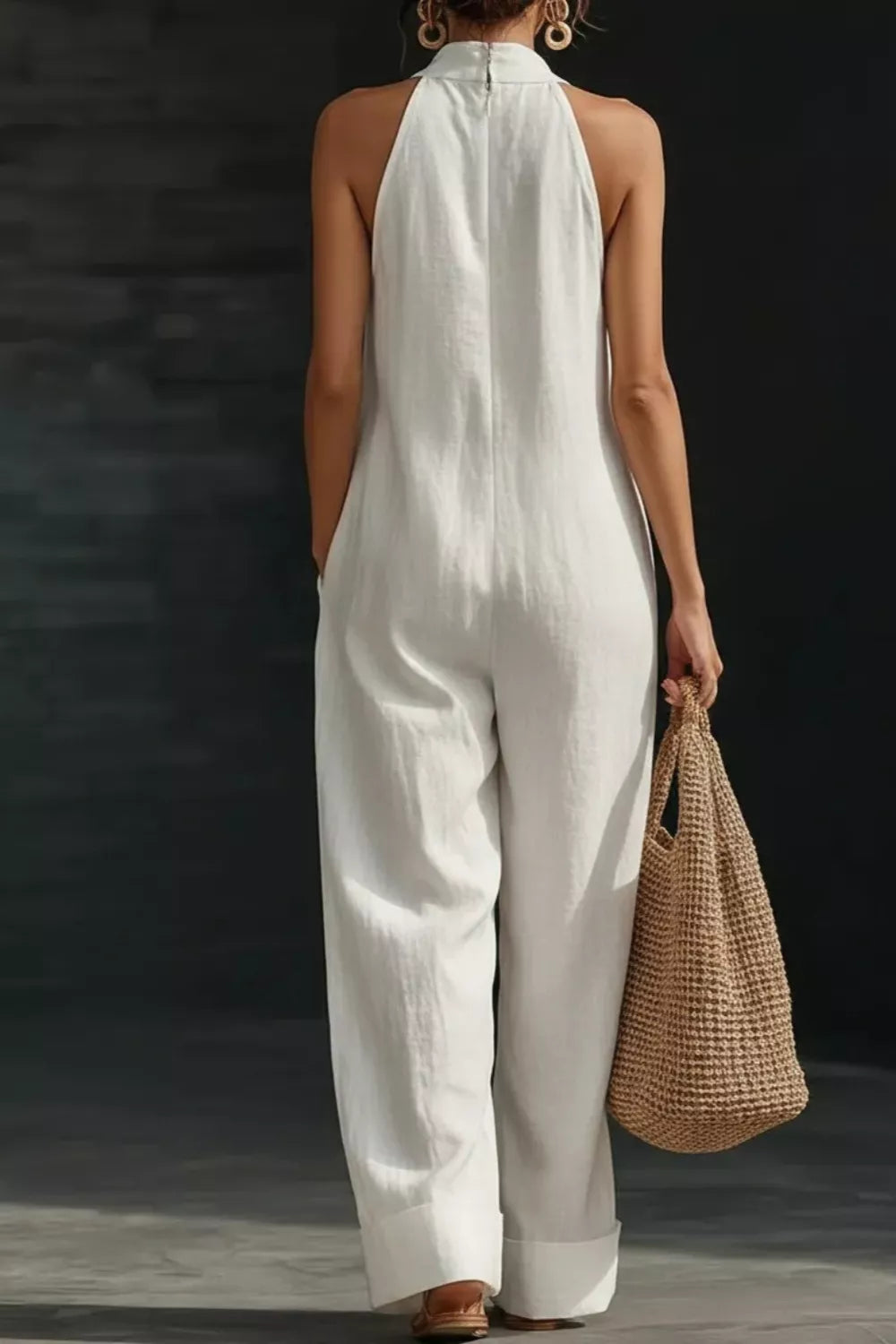 Sleeveless cream linen wide-leg jumpsuit, back view with woven tote bag.