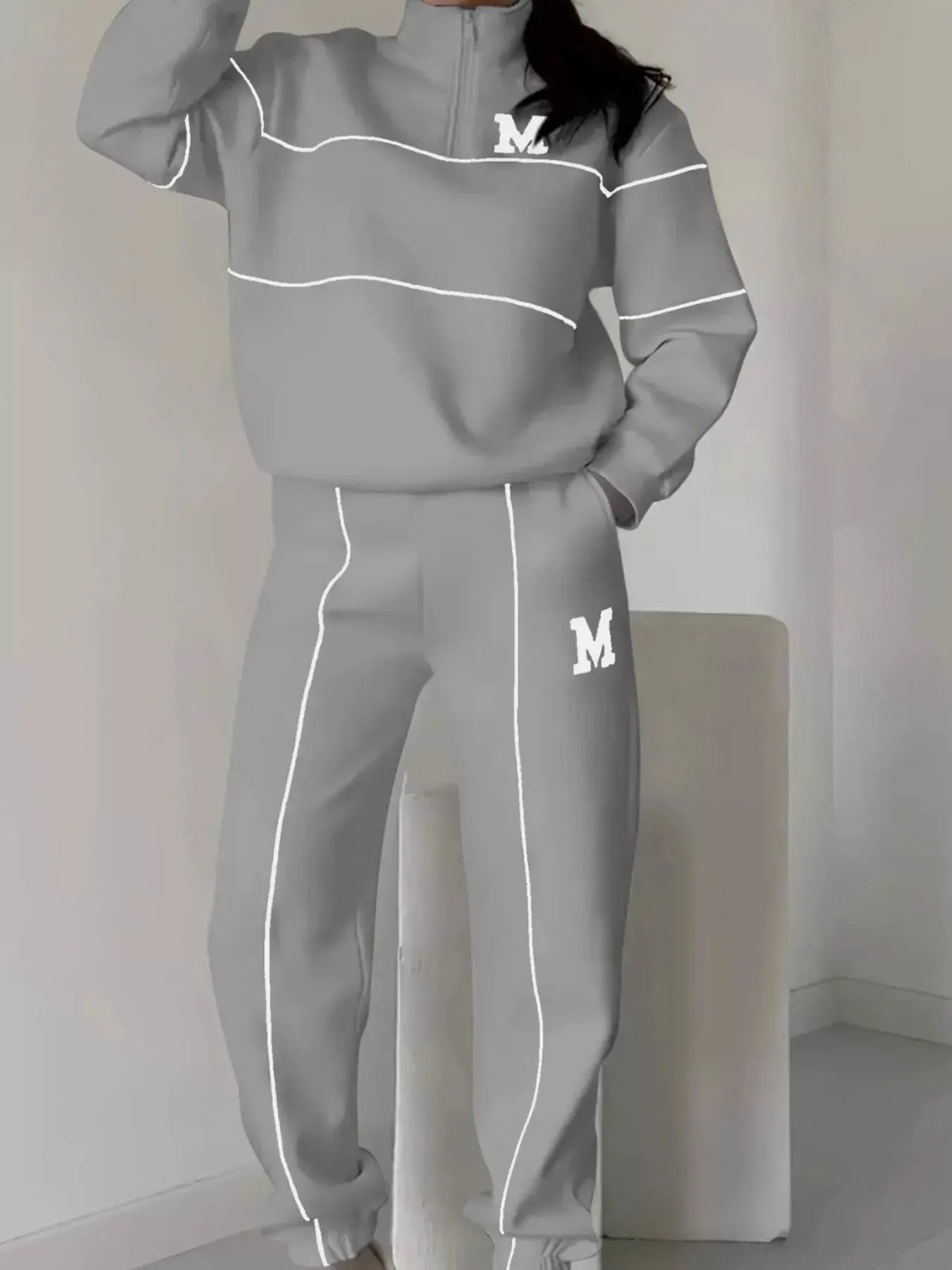 Plus-size striped quarter-zip top and pants set in gray with white piping and M logo.