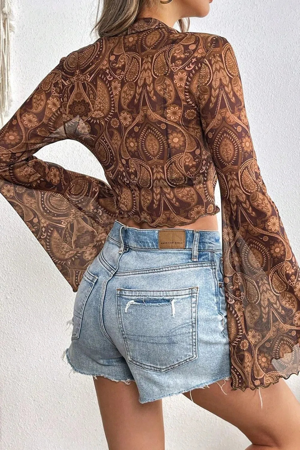 Printed Mock Neck Flare Sleeve Top in brown sheer paisley pattern; cropped fit with light denim shorts