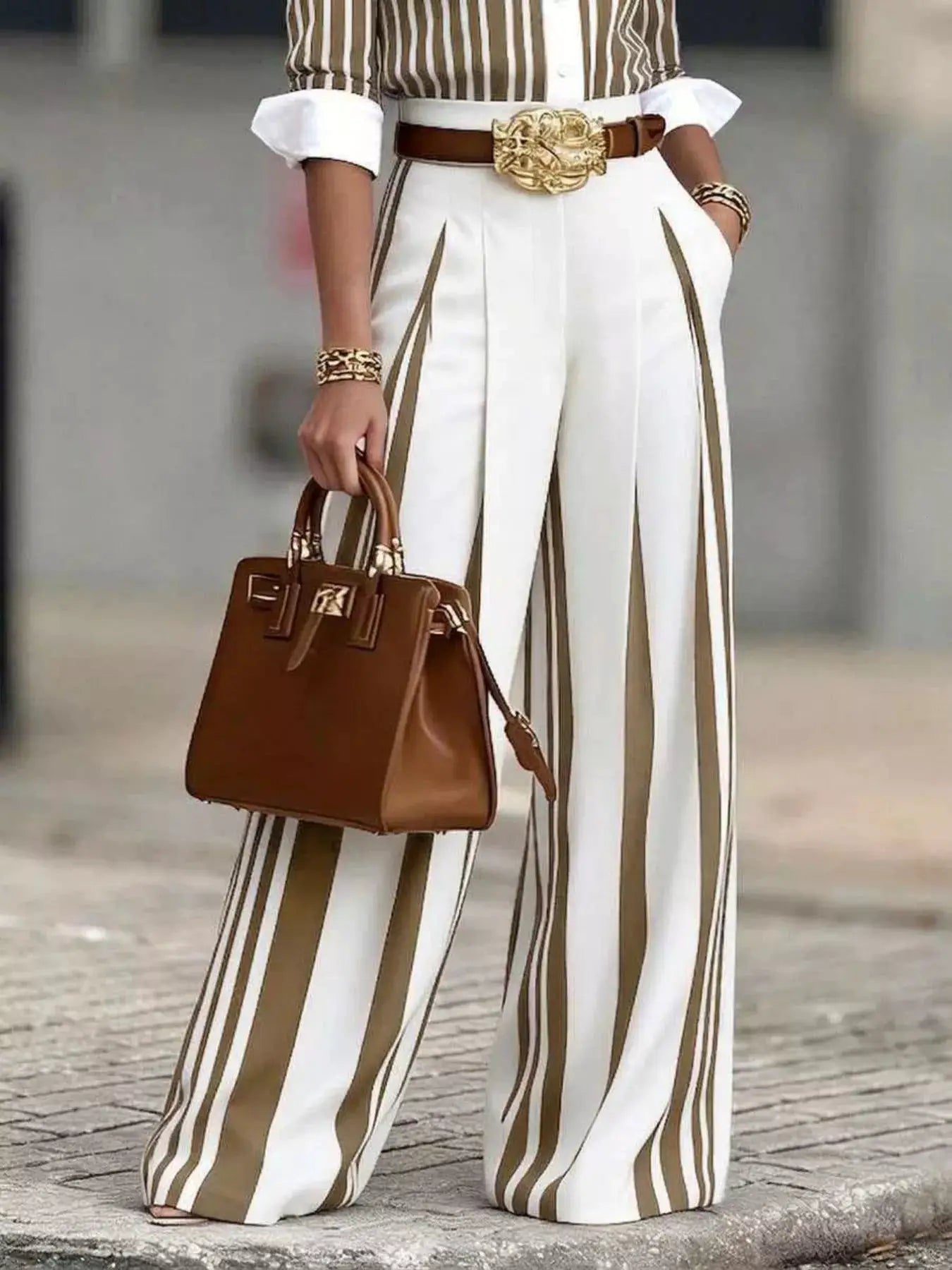 High-waisted wide-leg striped pants in white with tan stripes, paired with a brown belt and gold buckle.