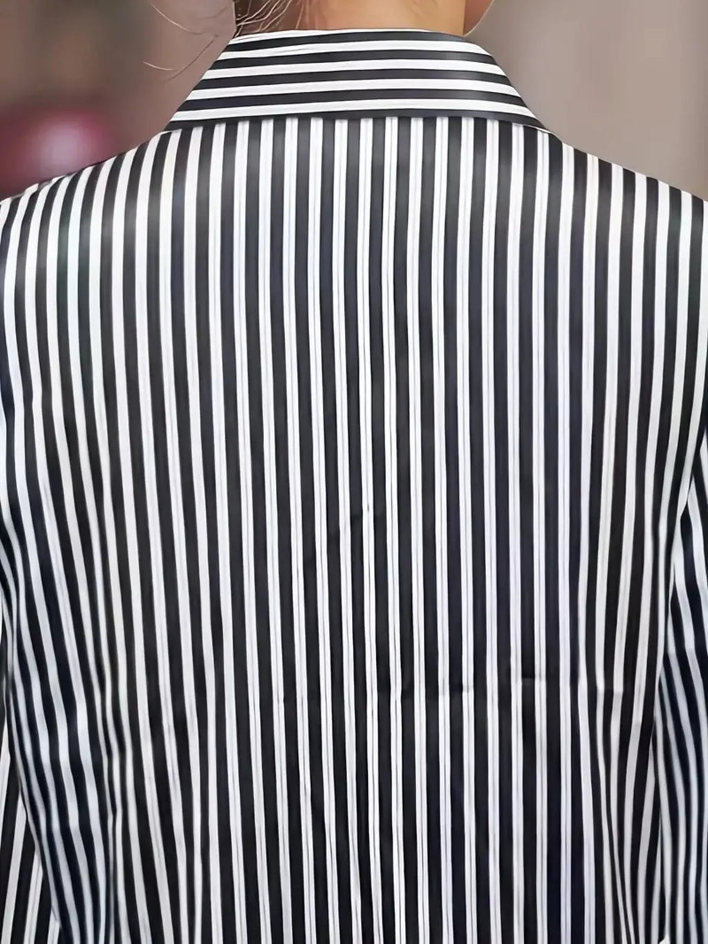 Striped long-sleeve shirt with vertical black and white stripes, back view.