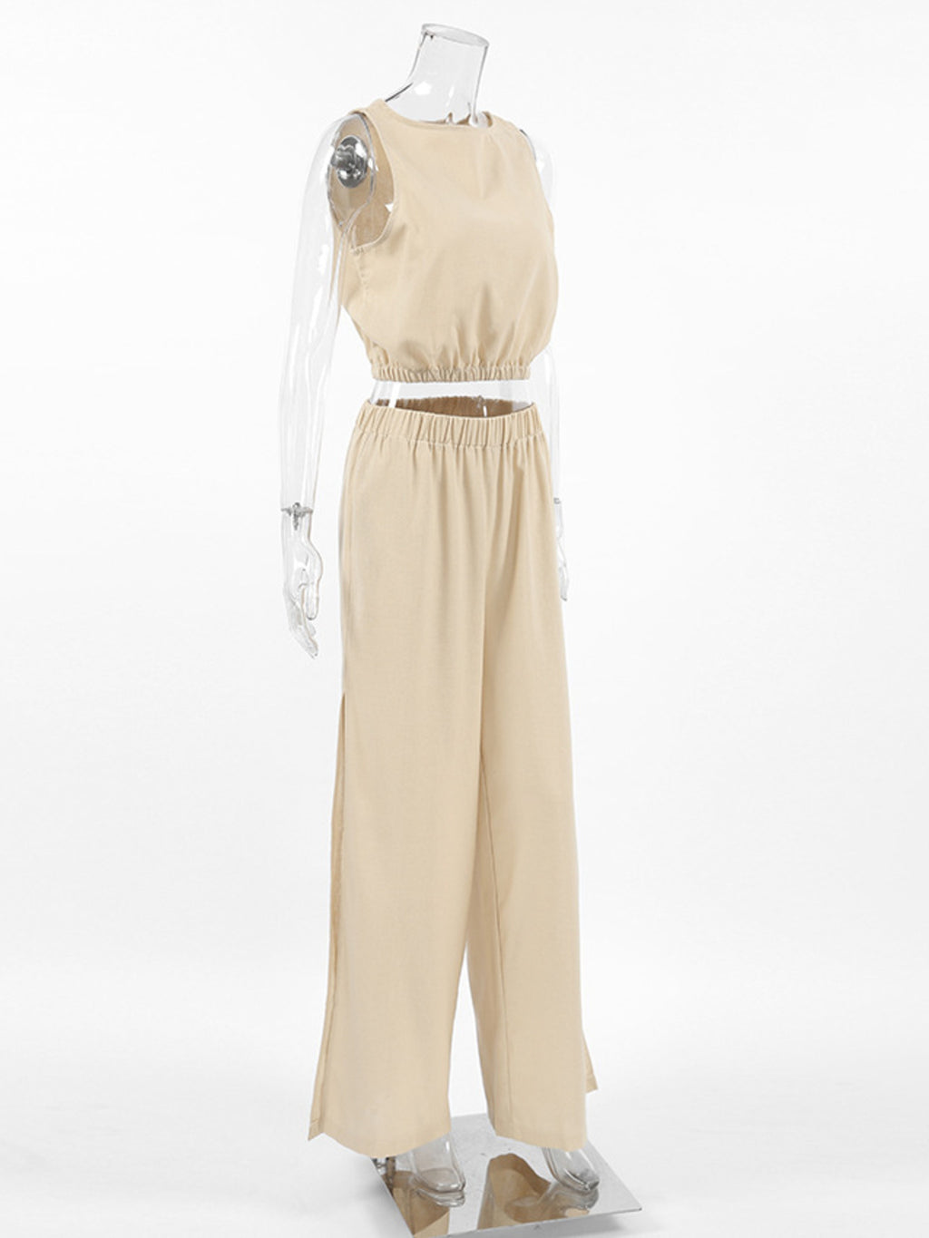 Sleeveless crop top and slit pants set in beige with elastic waist and wide-leg silhouette.