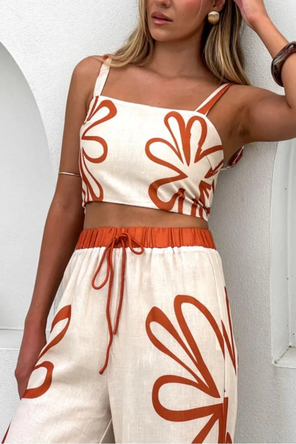 Two-piece smocked square-neck cami and pants set in ivory with rust-orange floral print; drawstring waist