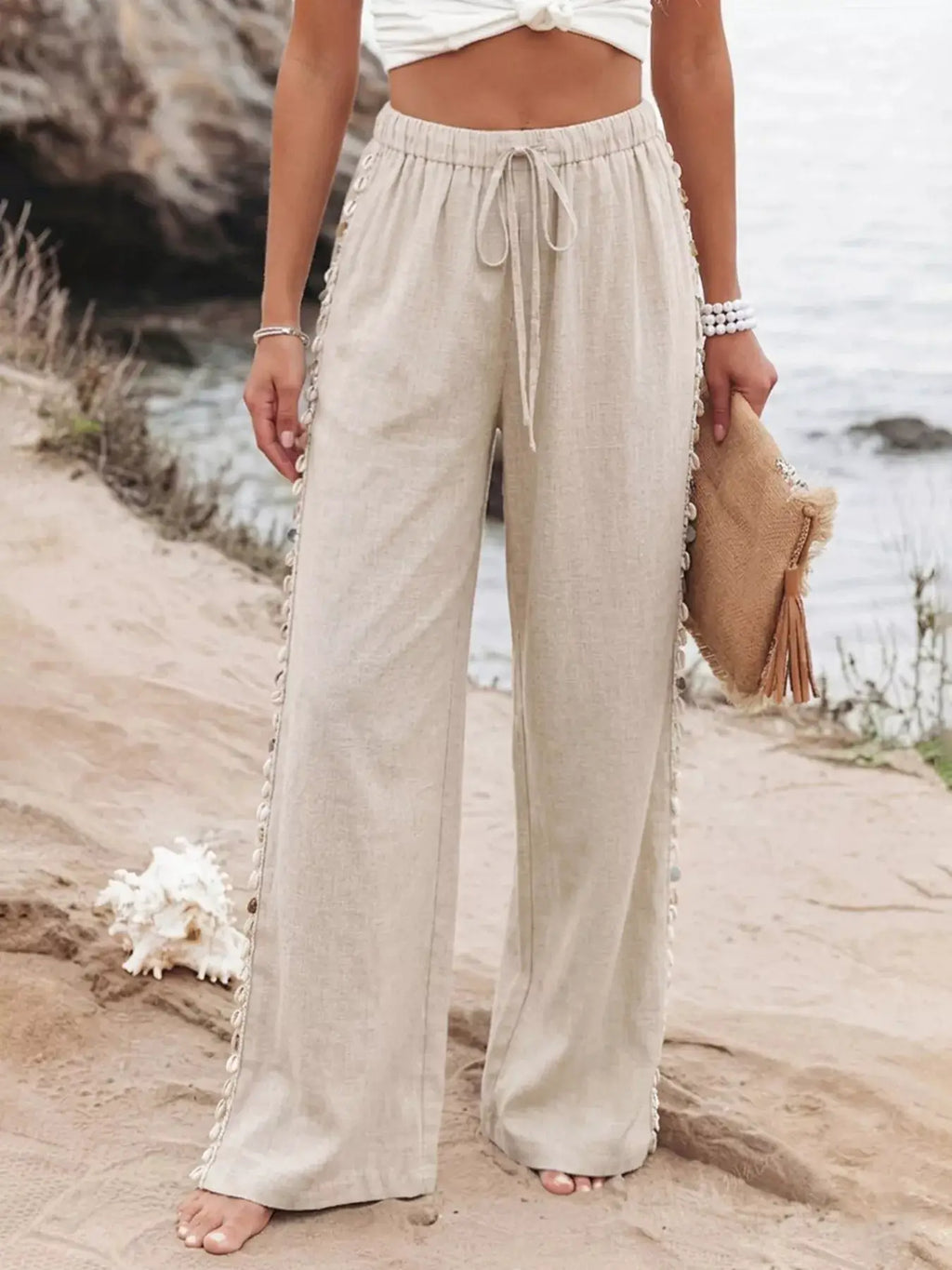 Drawstring beige wide-leg linen pants with shell bead trim along the sides