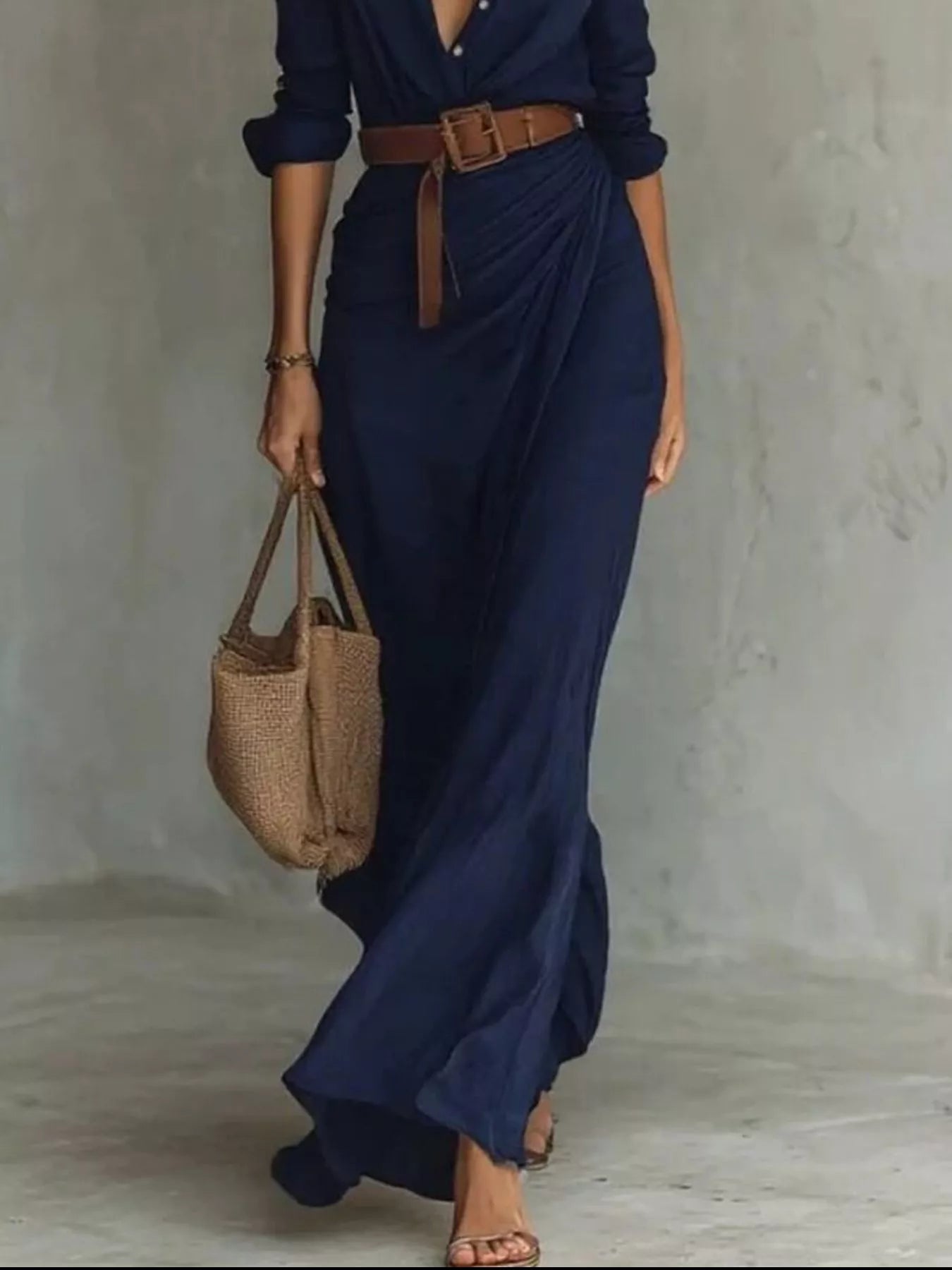 Full Size Ruched Long Sleeve Maxi Dress Plus Size in navy blue with belted waist; paired with a woven straw tote
