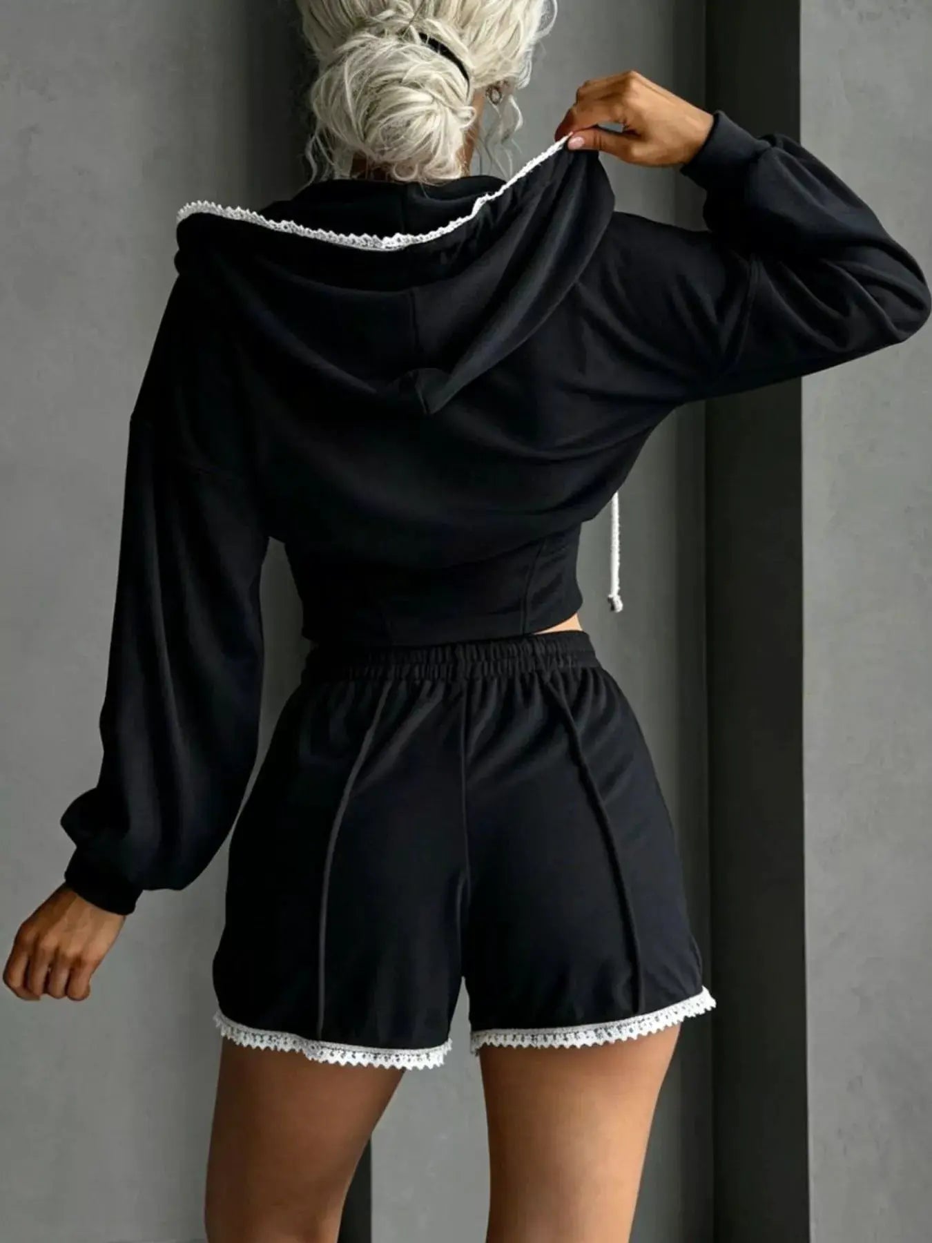 Two-piece Belle Bijouix activewear set: black zip-up hooded jacket with white lace trim and matching black shorts
