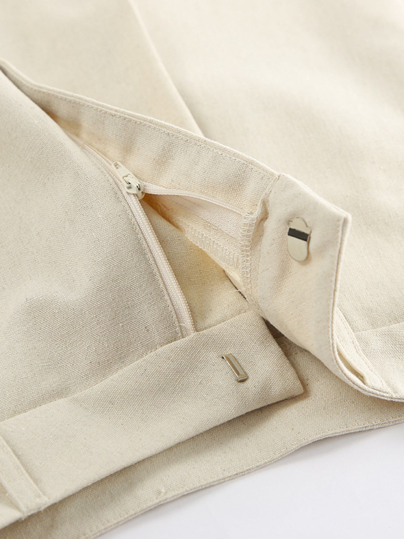 Beige two-piece button-up vest and shorts set with pocketed design; close-up shows zipper, snaps, and tonal hardware