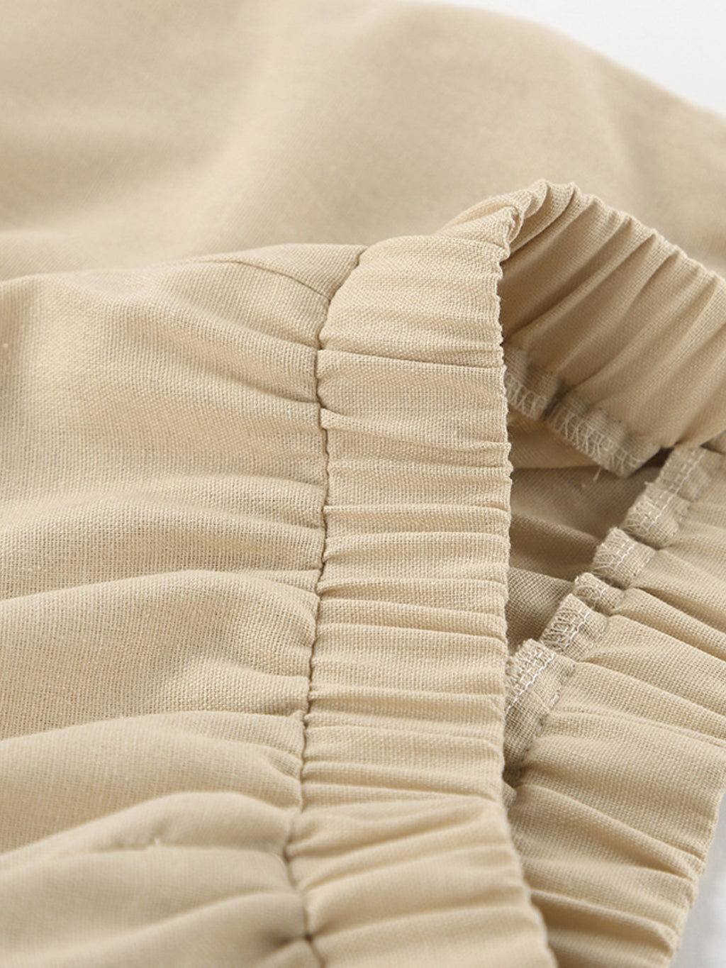Sleeveless crop top and slit pants set in beige ribbed fabric with ruched elastic detail.