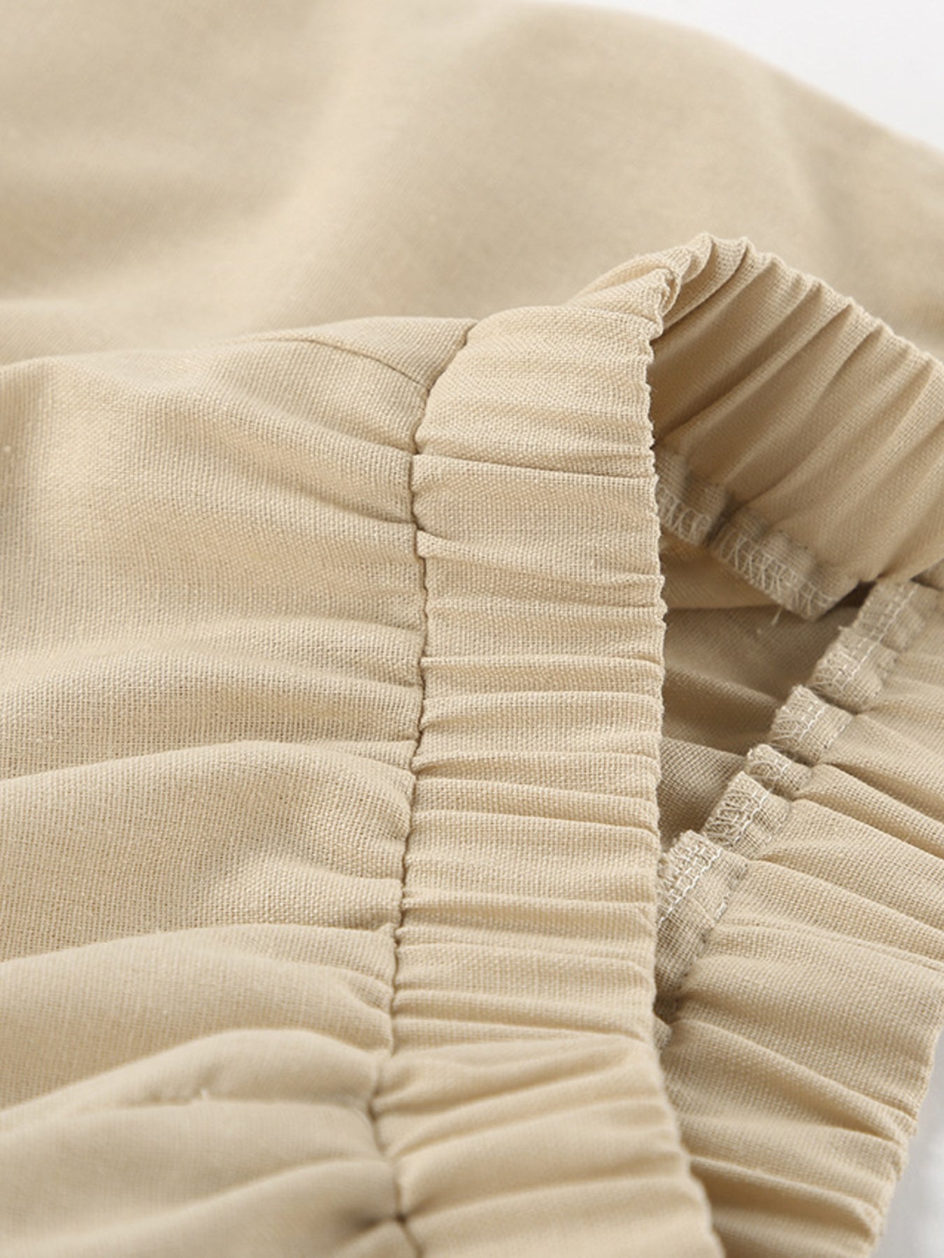 Sleeveless crop top and slit pants set in beige ribbed fabric with ruched elastic detail.