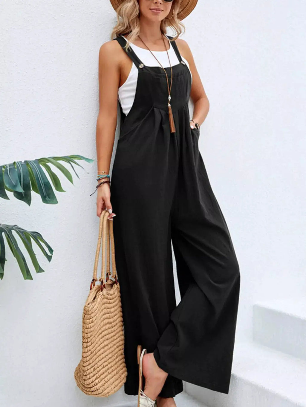 Plus-size black wide-leg one-piece overalls with pockets, worn with a white top.