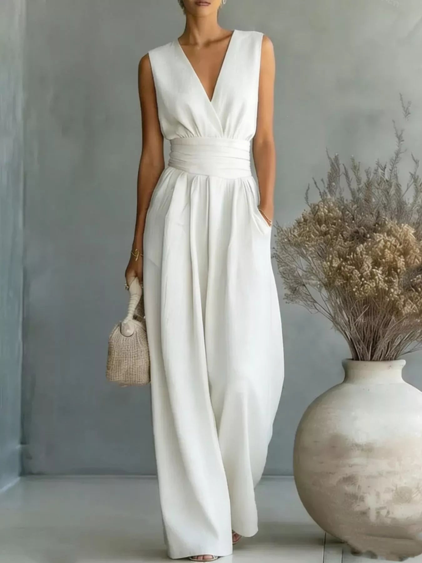 Plus-size sleeveless ivory wide-leg jumpsuit with wrapped V-neck and ruched waist.