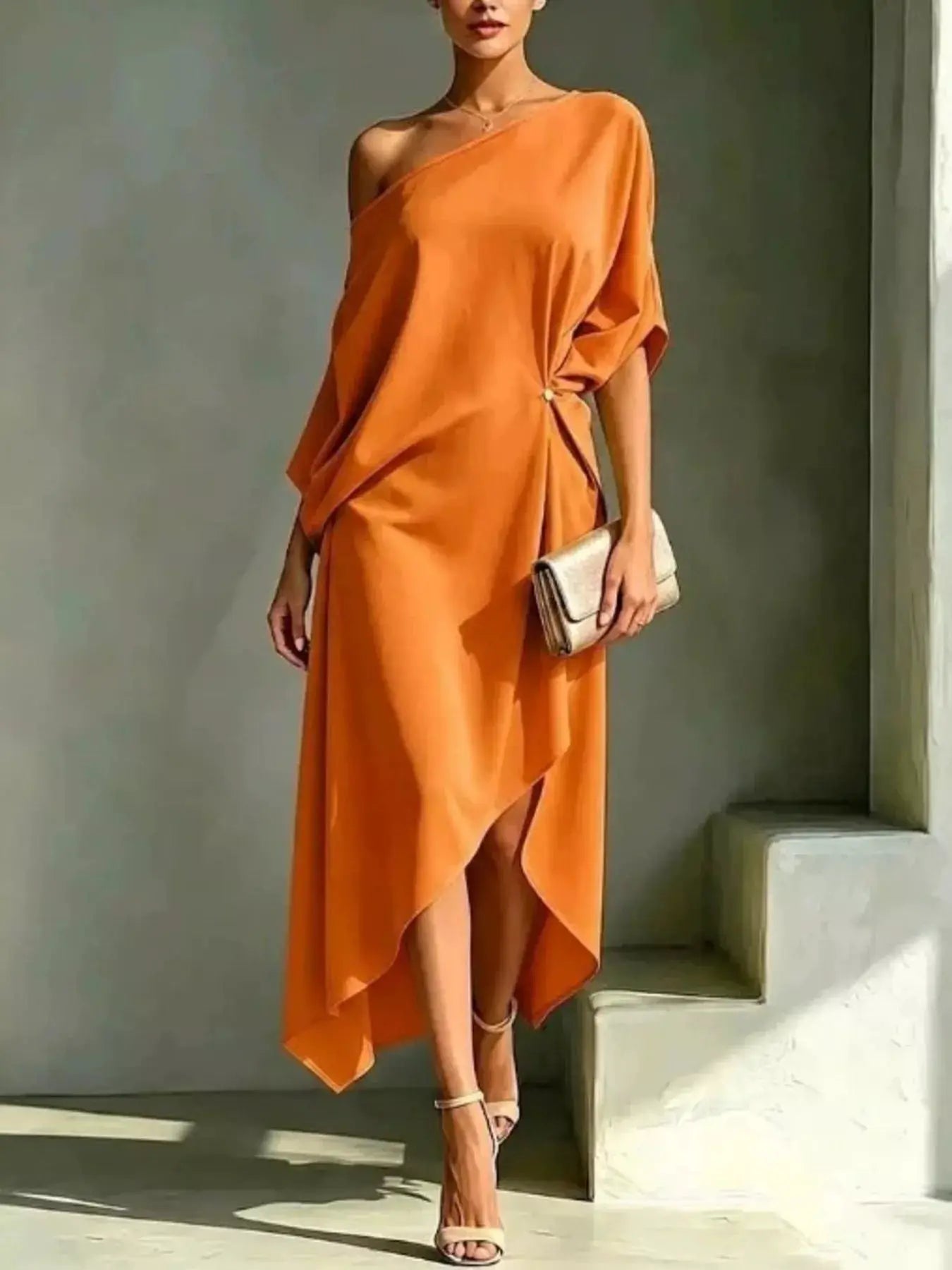 Plus Size Asymmetrical One Shoulder Drape Dress by Belle Bijouix, orange fabric with waist wrap and beige clutch.