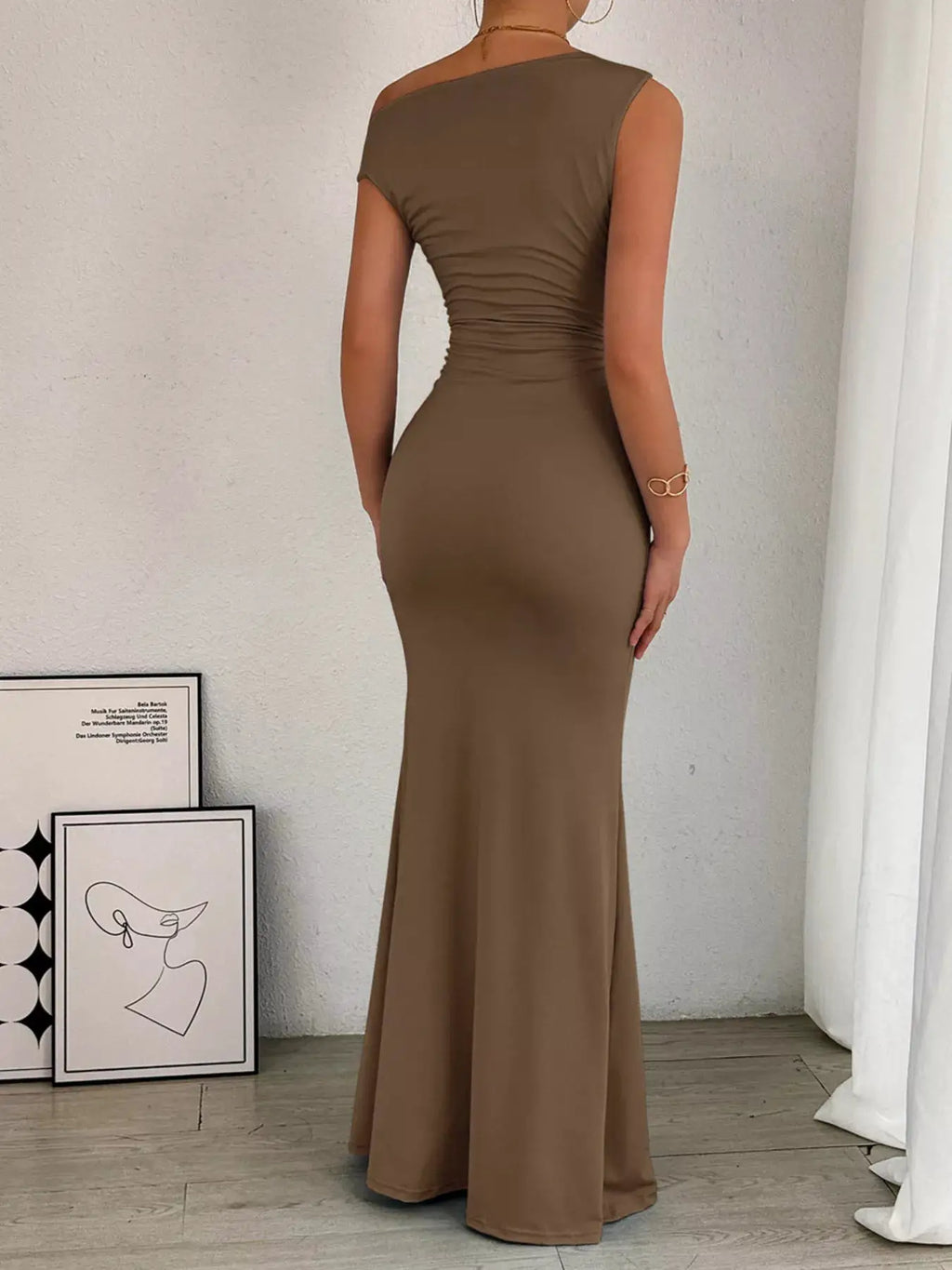 One-shoulder ruched bodycon maxi dress in taupe, back view with a fitted waist and flared hem.