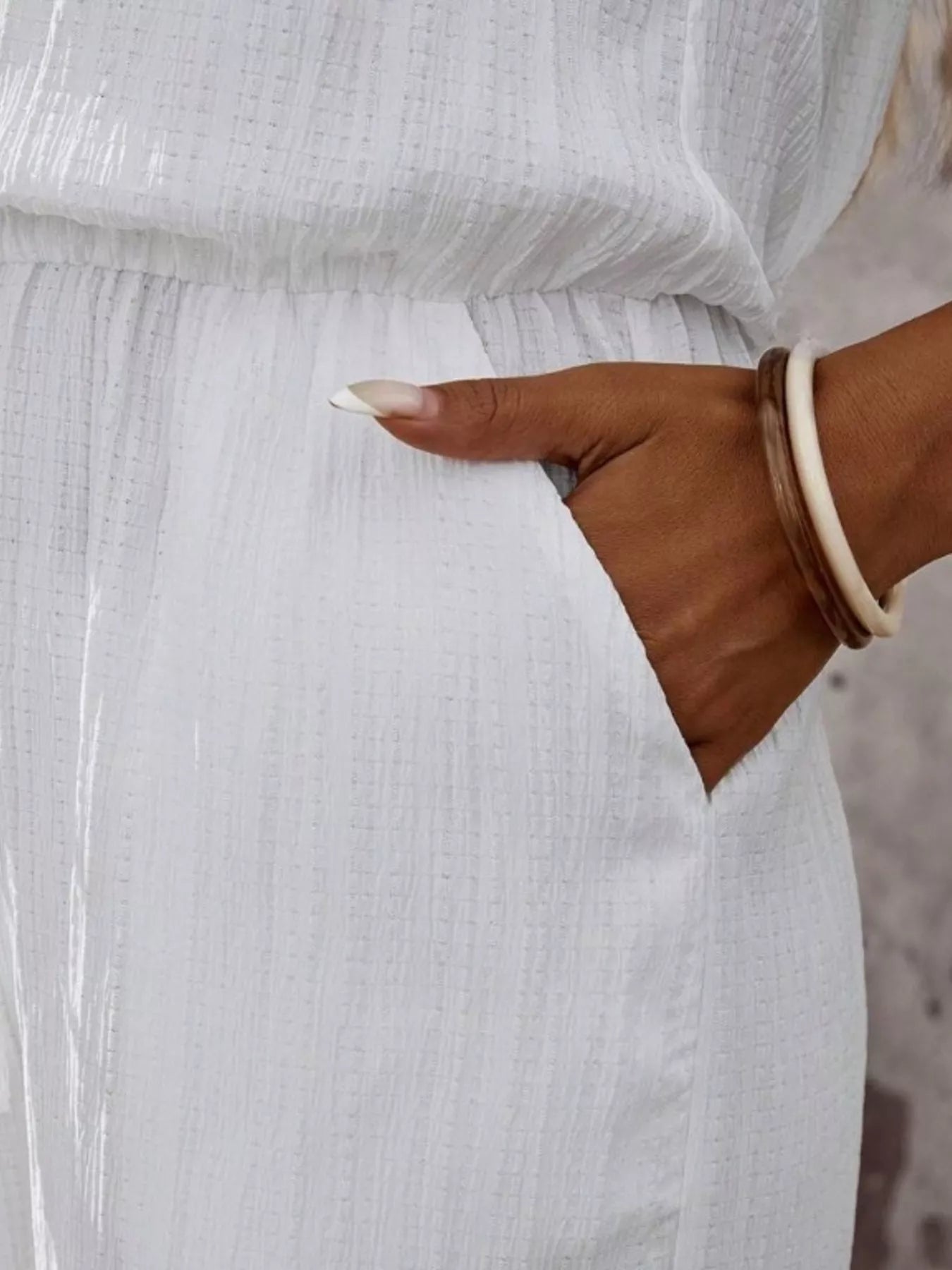 Trendsi full-size tassel sleeveless wide-leg jumpsuit in white textured fabric with pocket detail.