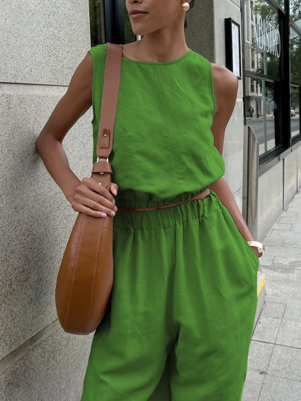 Sleeveless crop top and slit pants set in bright lime green with elastic waist, worn with a tan crossbody bag.