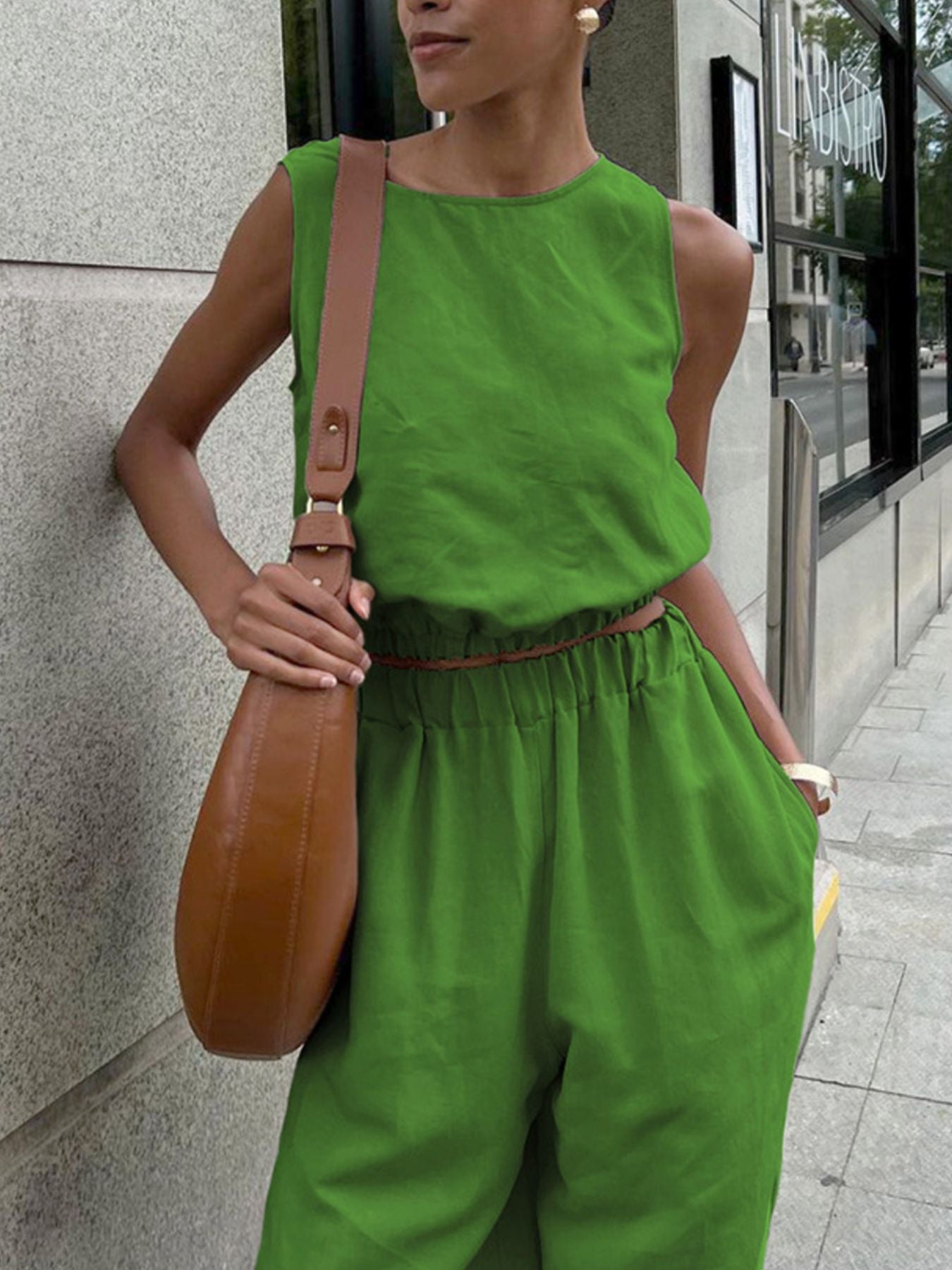 Sleeveless crop top and slit pants set in bright lime green with elastic waist, worn with a tan crossbody bag.