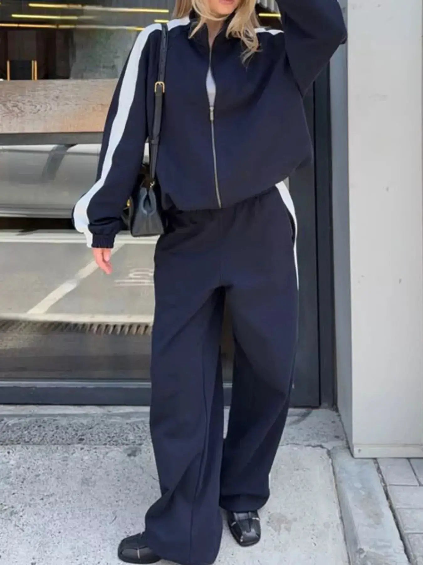 Two-piece navy zip-up activewear set with white stripe sleeves and matching pants