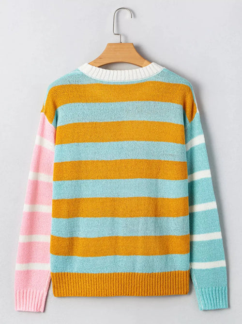 Color block striped sweater with orange and light blue bands and pink left sleeve, white ribbed crew neck.