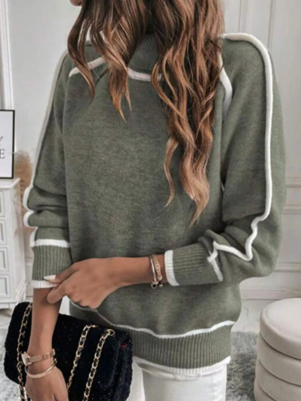 Military green turtleneck sweater with one sleeve pushed up and contrast-trim hem visible
