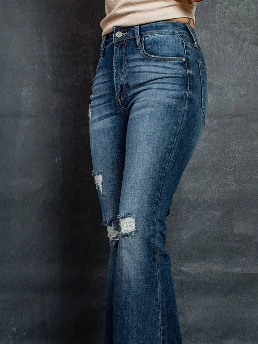 Distressed high-waisted flare jeans in blue denim with ripped patches and pockets