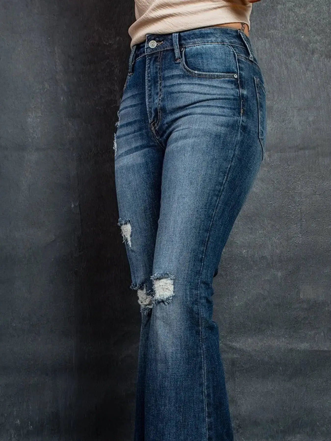 Distressed high-waisted flare jeans in blue denim with ripped patches and pockets